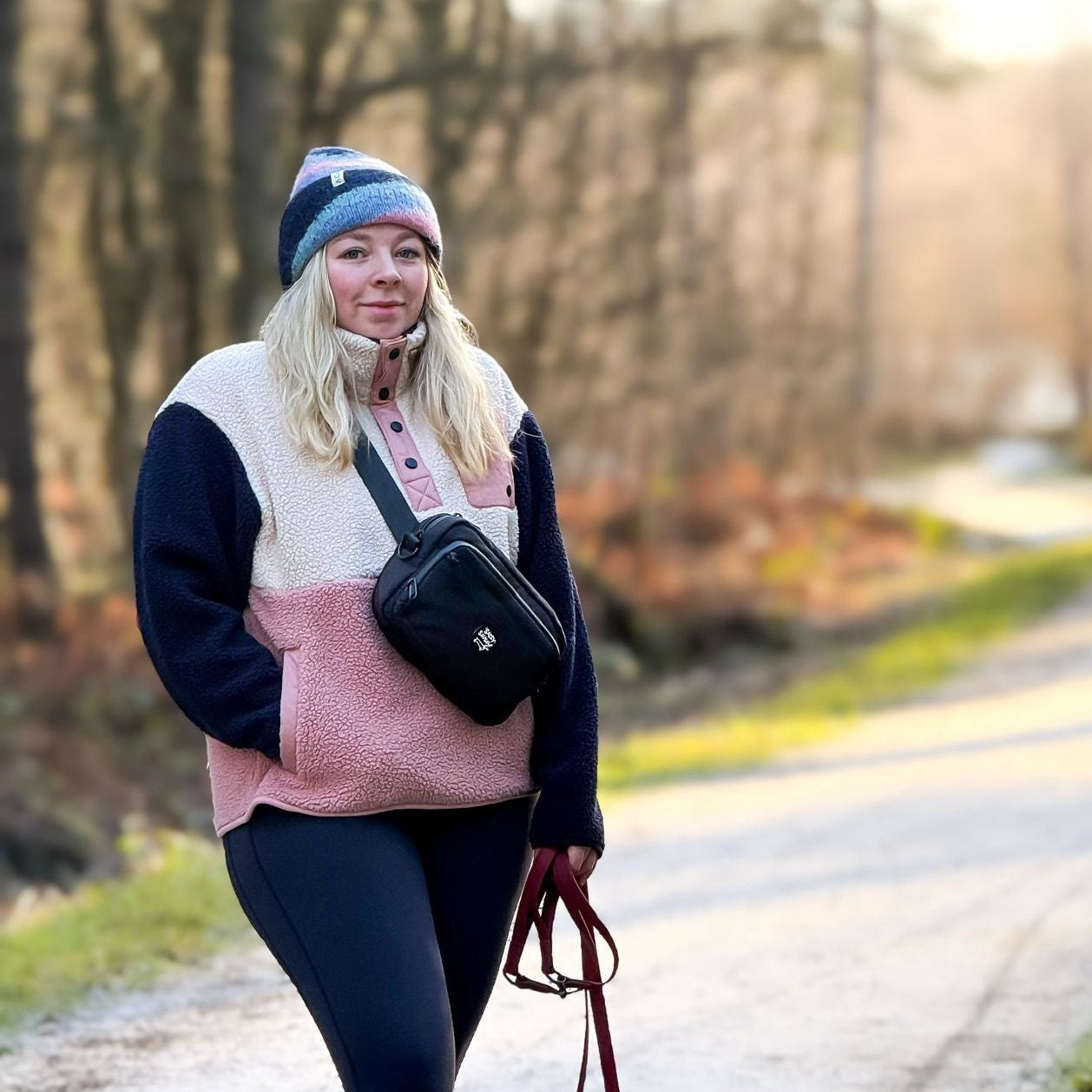 Woman walking two dogs on a path in a forested area