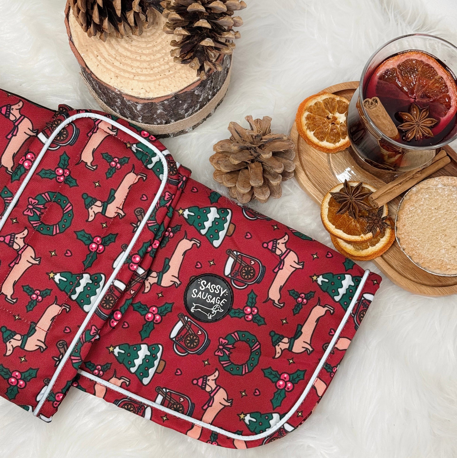 Red patterned bag with festive design on a white surface with pinecones and a mug of hot drink.